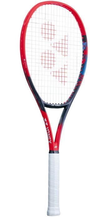 The Yonex VCORE 100L 2023 Tennis Racket - Scarlet is a visually impressive racket featuring a striking frame in red and black, designed for spin and speed. It prominently displays the Yonex logo on the frame and brand name on the neck, complemented by its sleek look with a comfortable white grip tape handle.