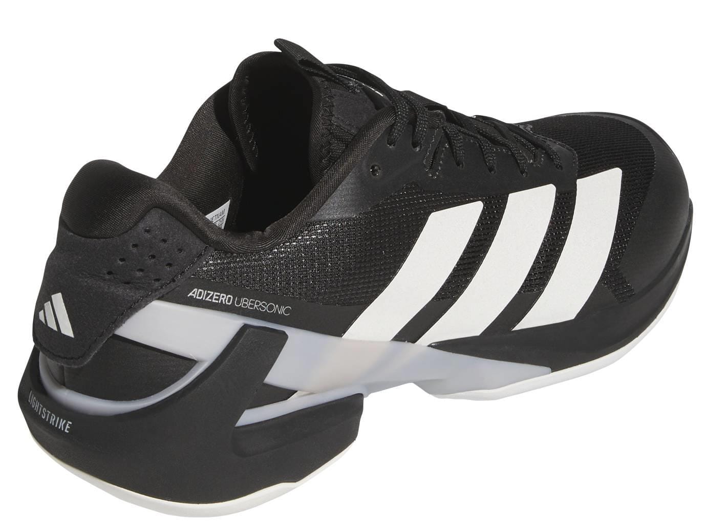 The ADIDAS Adizero Ubersonic 5 Men's Tennis Shoes in black by adidas feature white stripes, a white sole, and "ADIZERO UBERSONIC" on the side—shown from an angle highlighting the heel and outer side for optimal tennis performance.