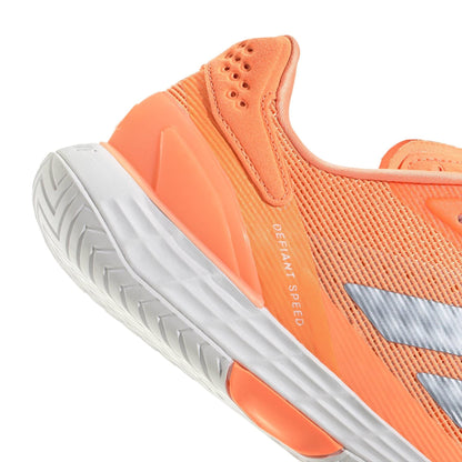 Close-up of the adidas Defiant Speed 2 Women's Tennis Shoes in orange, featuring a white sole, silver accents, “DEFIANT SPEED” printed near the heel, textured grip, and breathable mesh fabric for comfort.