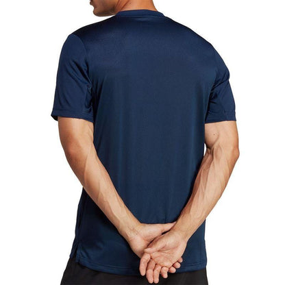 A man wearing an ADIDAS Men's Club Tennis T-Shirt in Navy stands with his back to the camera. His arms are crossed behind him, highlighting the sleek design of the AEROREADY fabric against a plain white background.