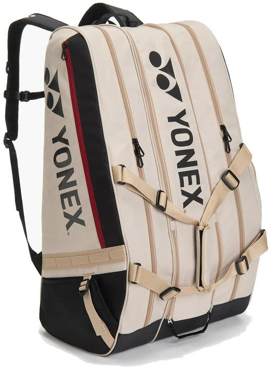 The Yonex BA726212EX Gearlogic 12 Racket Tennis Bag in beige features black straps, buckles, and a red zipper. The Yonex logo is printed on the side. Perfect as a self-standing tennis bag for easy access.