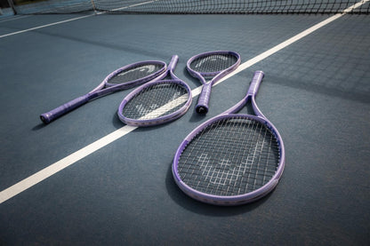 Four purple HEAD Boom MP L Alternate 2026 tennis rackets from HEAD rest on a blue court near the white boundary line, with the net in view.