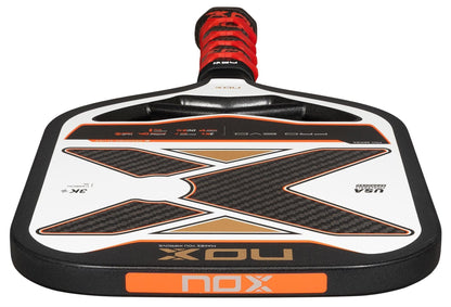 A close-up of the NOX Pro Evo Pickleball Paddle by NOX in black and red, highlighting its large X design on the 3K carbon fiber face and a matching wrapped handle.