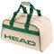 The HEAD Arthur Ashe Tennis Court Bag 40L in white and green features green handles, trim, a bold HEAD logo on the side, premium PU leather construction, and a front zipper pocket.
