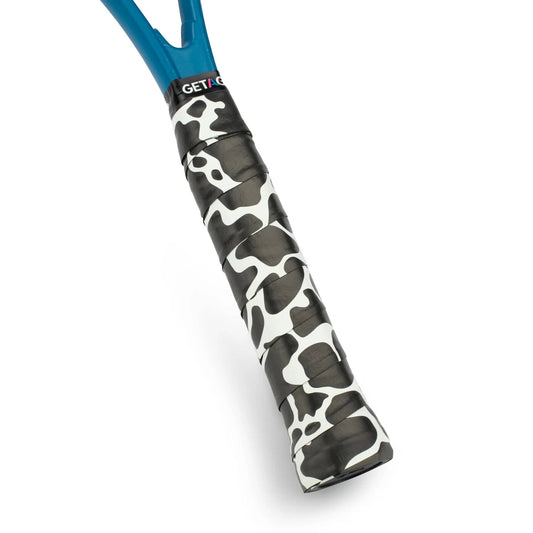 A close-up of the Get A Grip Cow-A-Bunga Tennis Overgrip in white and black cow pattern, showcasing its premium non-slip grip material, set against a plain white background.