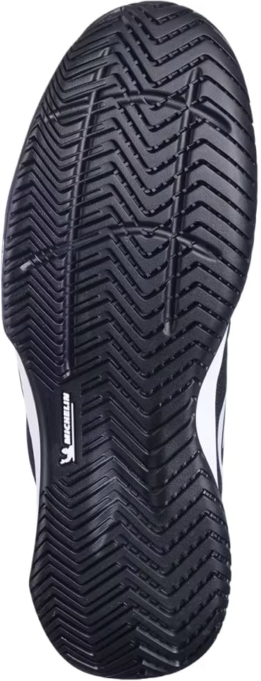 Close-up of the black sole of the Babolat SFX EVO All Court Men's Tennis Shoe, showcasing a zigzag tread pattern and a white Michelin logo near the center, emphasizing the shoe's durable design by Babolat.