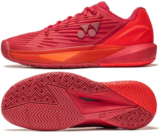 The Yonex Power Cushion Eclipsion 5 Men's Tennis Shoes in Ruby Red are shown from the side and bottom, featuring a herringbone sole, geometric upper design, and a Yonex logo with two circles and a triangle on the side.