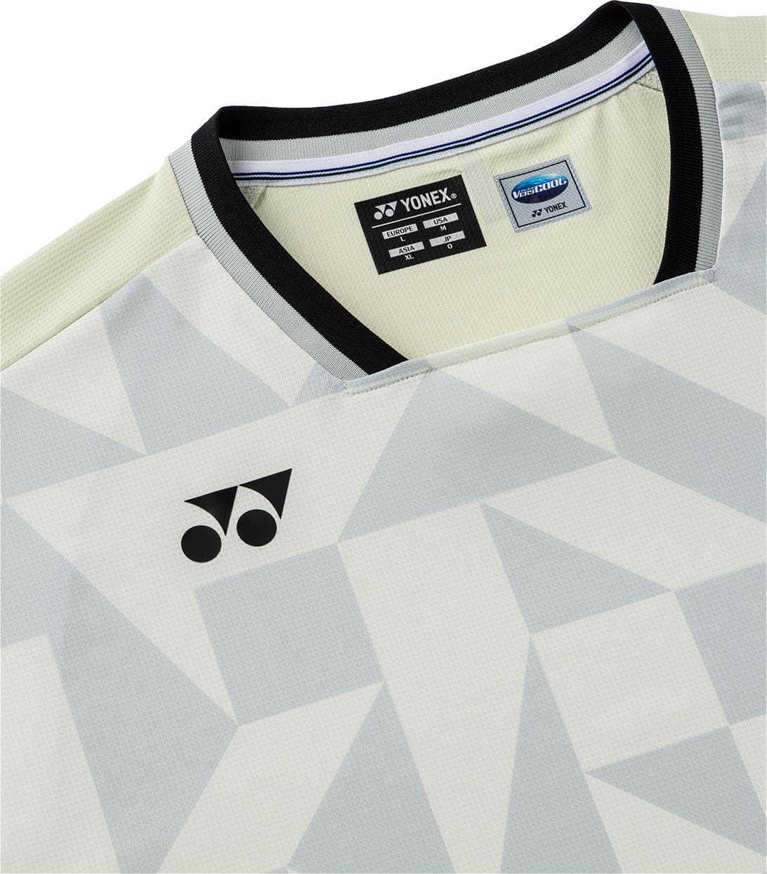 Close-up of the Yonex 10712YX Crew Neck Men's Tennis T-Shirt in Champagne, featuring a geometric pattern, black crew neck trim, and Yonex logo on the chest. Clothing tags are visible inside the neckline.