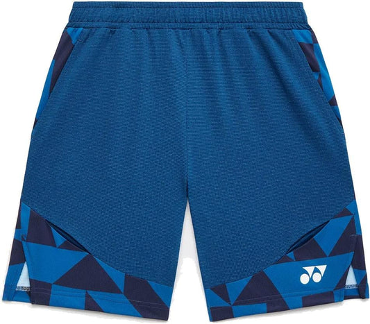 The Yonex 15240YX Knit Men’s Tennis Shorts in Indigo Blue feature an elastic waistband, geometric blue side panels, a white front logo, and breathable knit fabric for comfort.