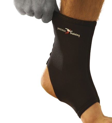A person wearing a black Precision Neoprene Ankle Support from the Precision brand demonstrates how the support aids in recovering from minor sprains. The ankle support effectively covers the ankle, providing necessary support while the individual holds their lower leg to showcase its usefulness.