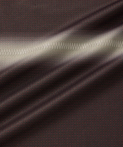 Close-up of black fabric with subtle red dots from the Yonex 10711YX Crew Neck Mens Tennis T-Shirt; a zigzag seam runs horizontally, and soft light highlights the moisture-wicking texture and gentle folds.