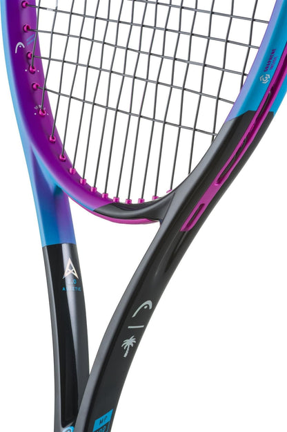 Close-up of two tennis rackets, including the HEAD Radical MP Palm Tree Crew Tennis Racket in Black/Pink/Blue with modern design and white logos, showing overlapping strings and part of their handles.