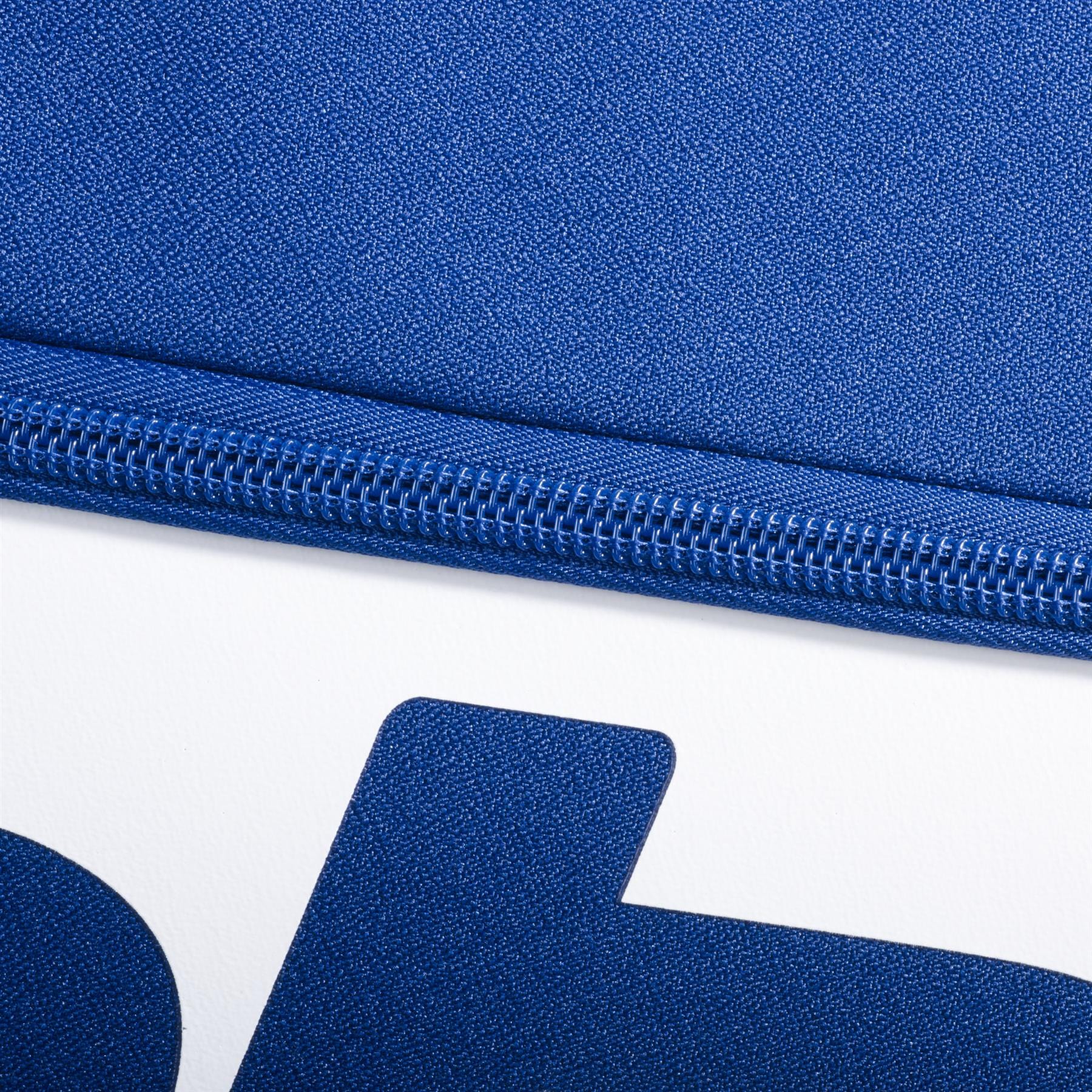 A close-up of a blue zipper on textured blue fabric, partially unzipped to show a white surface with a bold dark blue design—part of the Babolat Court M 6 Racket Tennis Bag by Babolat.