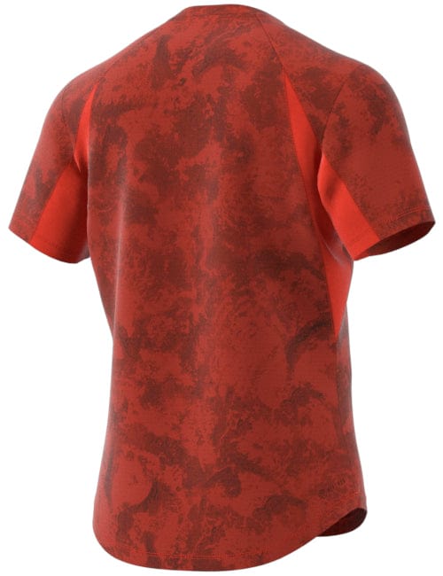 The ADIDAS Paris Mens Freelift Tennis T-Shirt in Red by adidas boasts a textured, camo-inspired pattern with darker red patches for an abstract appearance. Its HEAT.RDY design is prominently displayed from the back, highlighting its casual fit and raglan sleeves.