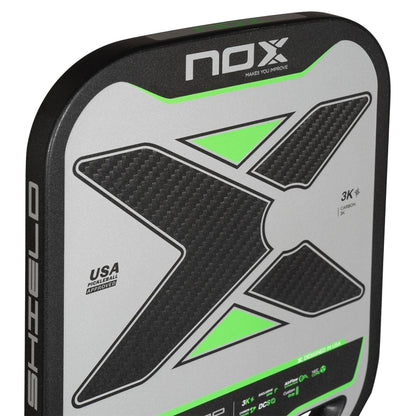 Close-up of the NOX NOV Pro Shield Pickleball Paddle in black/green, featuring a bold black "X" with green accents, carbon fiber texture, and text "USA Pending Approval" and "3K CARBON," showcasing advanced spin technology.
