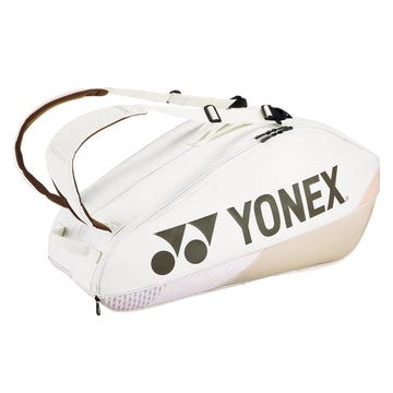 The Yonex 92426EX 6 Racket Pro Tennis Bag in sand beige boasts a sleek, curved design with two shoulder straps and proudly displays a large Yonex logo on the side. It offers multiple compartments for convenient storage.