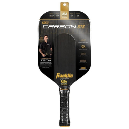 The Franklin Carbon STK 14.5mm Pickleball Paddle - Black by Franklin comes in black packaging with product info, graphics, and the yellow Franklin logo. A man holding this USA Pickleball approved paddle is pictured on the left side.