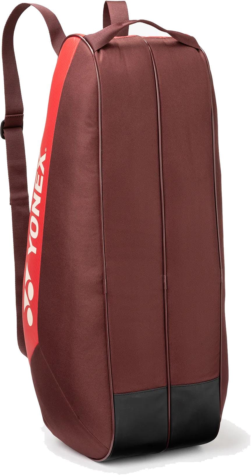 The Yonex 42526EX Team 6 Racket Tennis Bag in Ruby Red features a shoulder strap, top handle, durable black-reinforced corners, and a white Yonex logo on the side. It stands upright and holds up to six rackets.