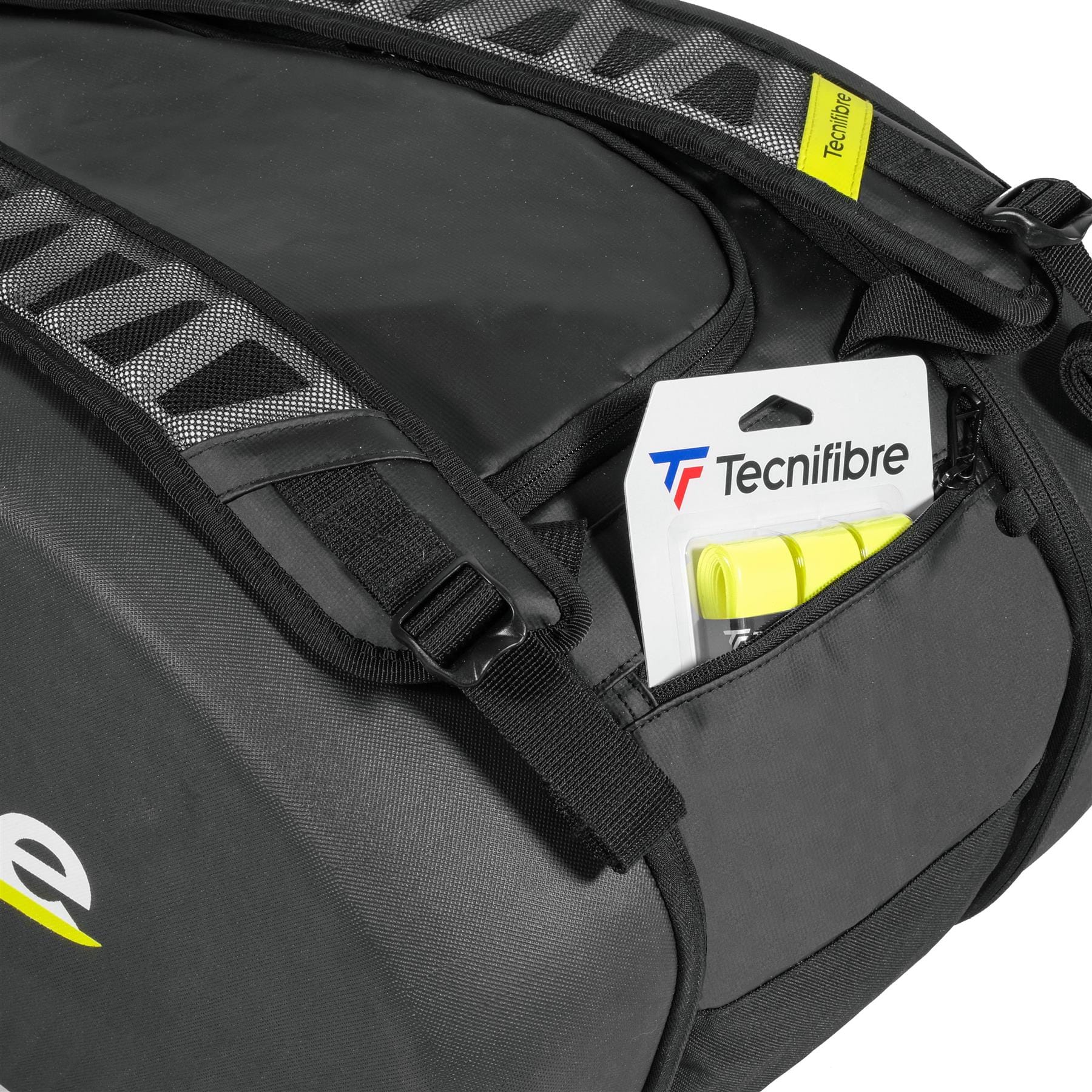 A close-up of the spacious Tecnifibre Reform L Tennis Racket Bag - Black shows gray and yellow accents, a padded shoulder strap, and a Tecnifibre tennis grip partly visible in an outer zippered pocket of the EVA material bag.