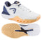 A pair of HEAD Revolt Pro 5.0 Womens Tennis Shoes in White/Apricot with orange soles, shown from the side and bottom. These durable shoes feature a geometric sole pattern and HEAD branding on the side.