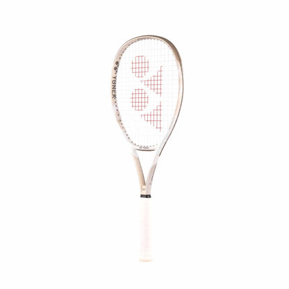 The Yonex VCORE Feel Tennis Racket in Sand Beige features a sleek frame with red markings on the strings. The handle is wrapped in white grip tape and complements the Yonex brand displayed on the side, elegantly integrating ISOMETRIC technology against a pristine backdrop.