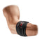A person's arm is equipped with a McDavid Tennis Elbow Strap With Pads, featuring black material, red stitching, and a logo. This strap wraps around the elbow to provide adjustable compression and pain-relieving pressure for optimal support.