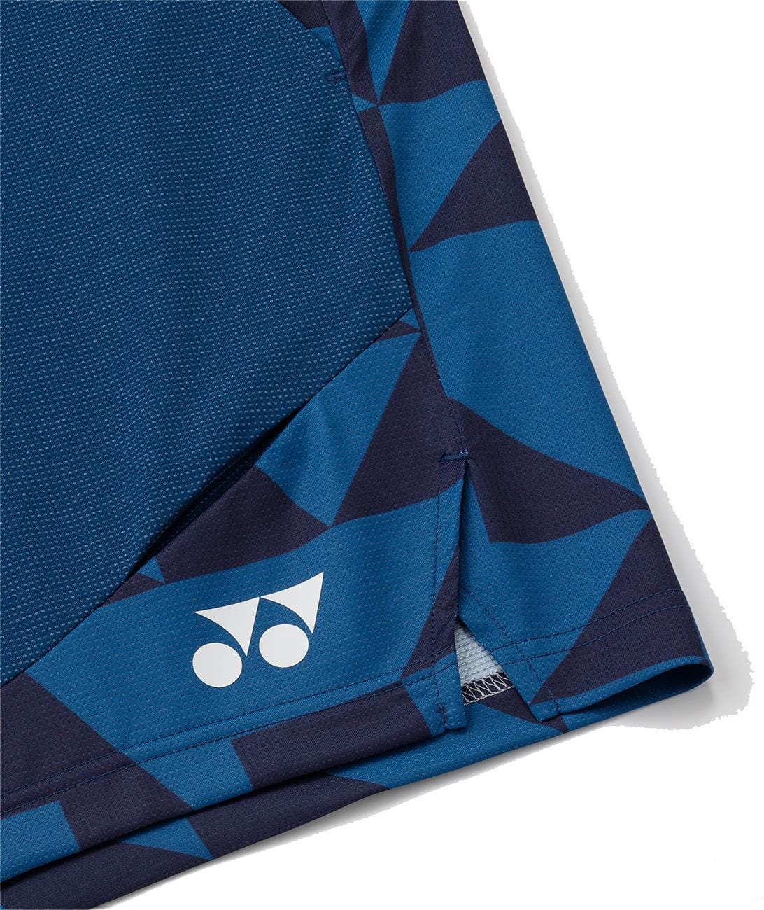 Close-up of Yonex 15240YX Knit Mens Tennis Shorts in indigo blue, made from breathable knit fabric with geometric dark blue patterns and a white Yonex logo near the vented hem.