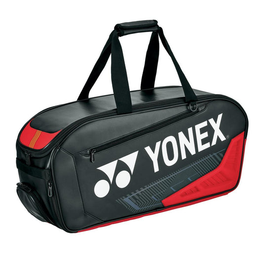 The Yonex 02331WEX Expert Tournament Tennis Bag, crafted in a stylish black and red rectangular design, features two straps for convenient carrying. Displaying the Yonex logo prominently in white on its side, this bag also includes a practical shoe pocket to keep your equipment organized.