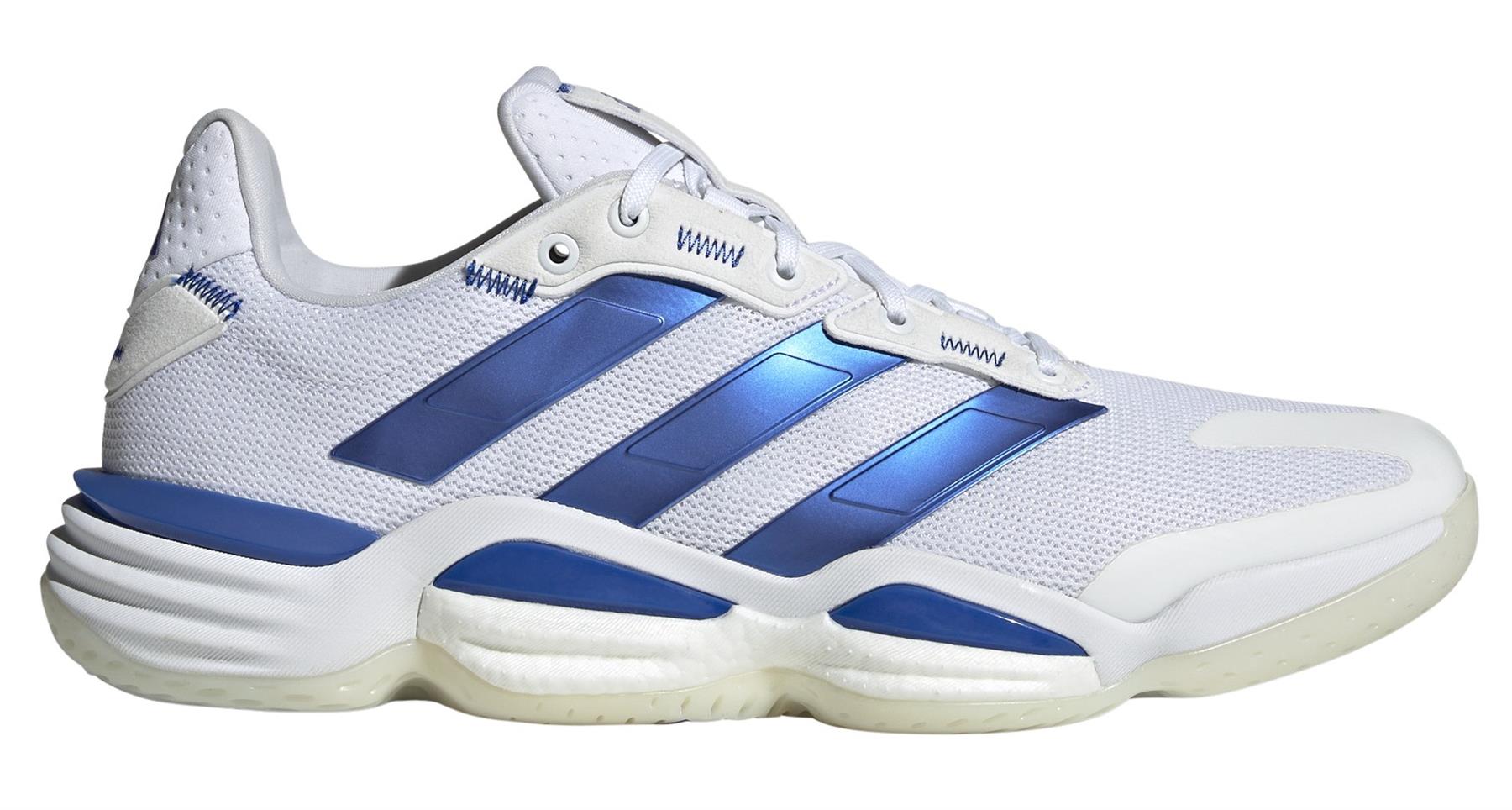 The ADIDAS Stabil 16 Mens Indoor Court Shoes in white and blue feature a mesh upper, textured sole, blue stripes, and accents. They include the signature BOOST midsole for comfort along with white laces and a sleek design.