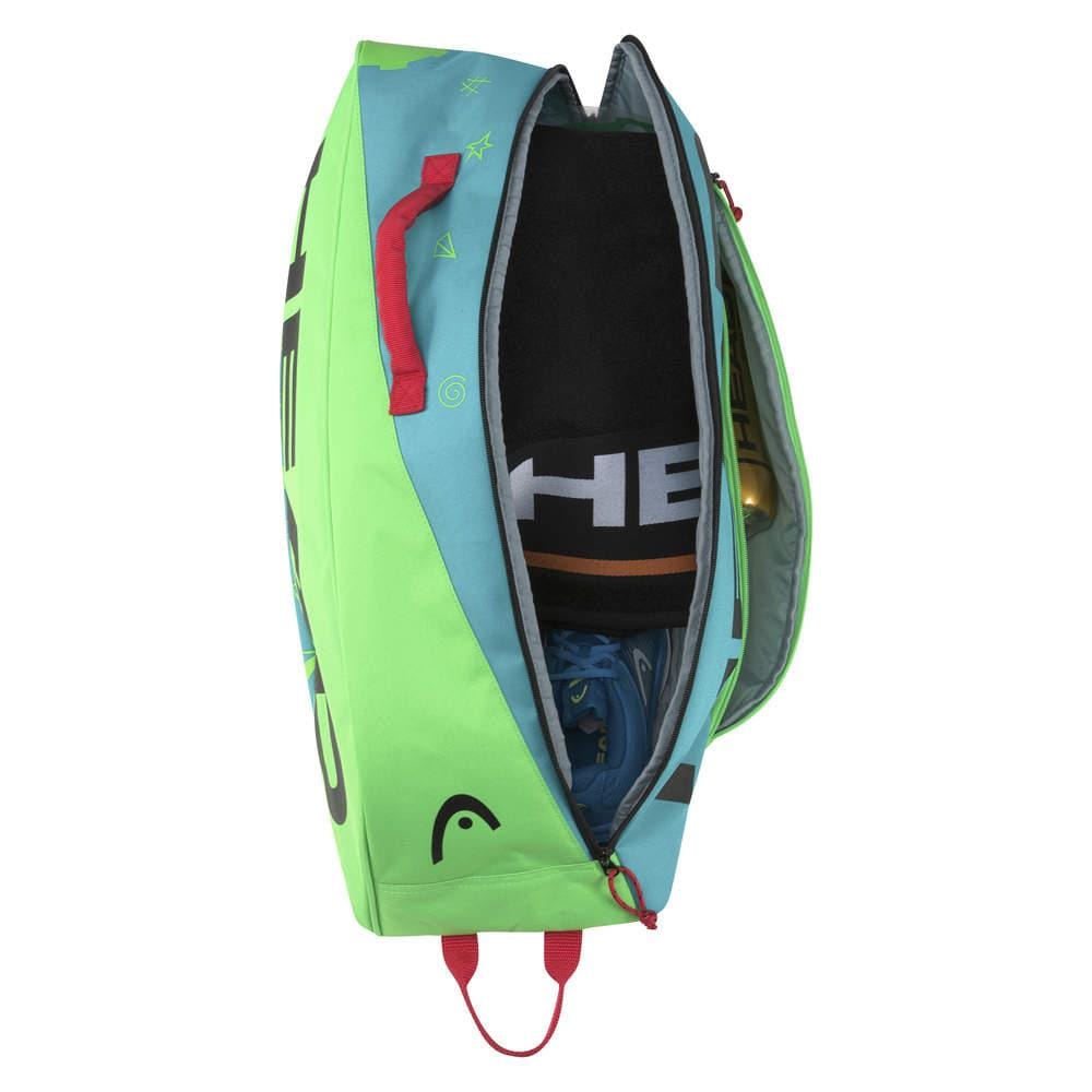 A partially open HEAD Junior Combi Novak 6 Racket Tennis Bag, with a blue and green exterior, reveals a rolled-up towel, blue athletic shoes, and a gold-colored water bottle. This bag, inspired by Novak Djokovic's style from the renowned brand HEAD, is accented with red handles and zipper details.