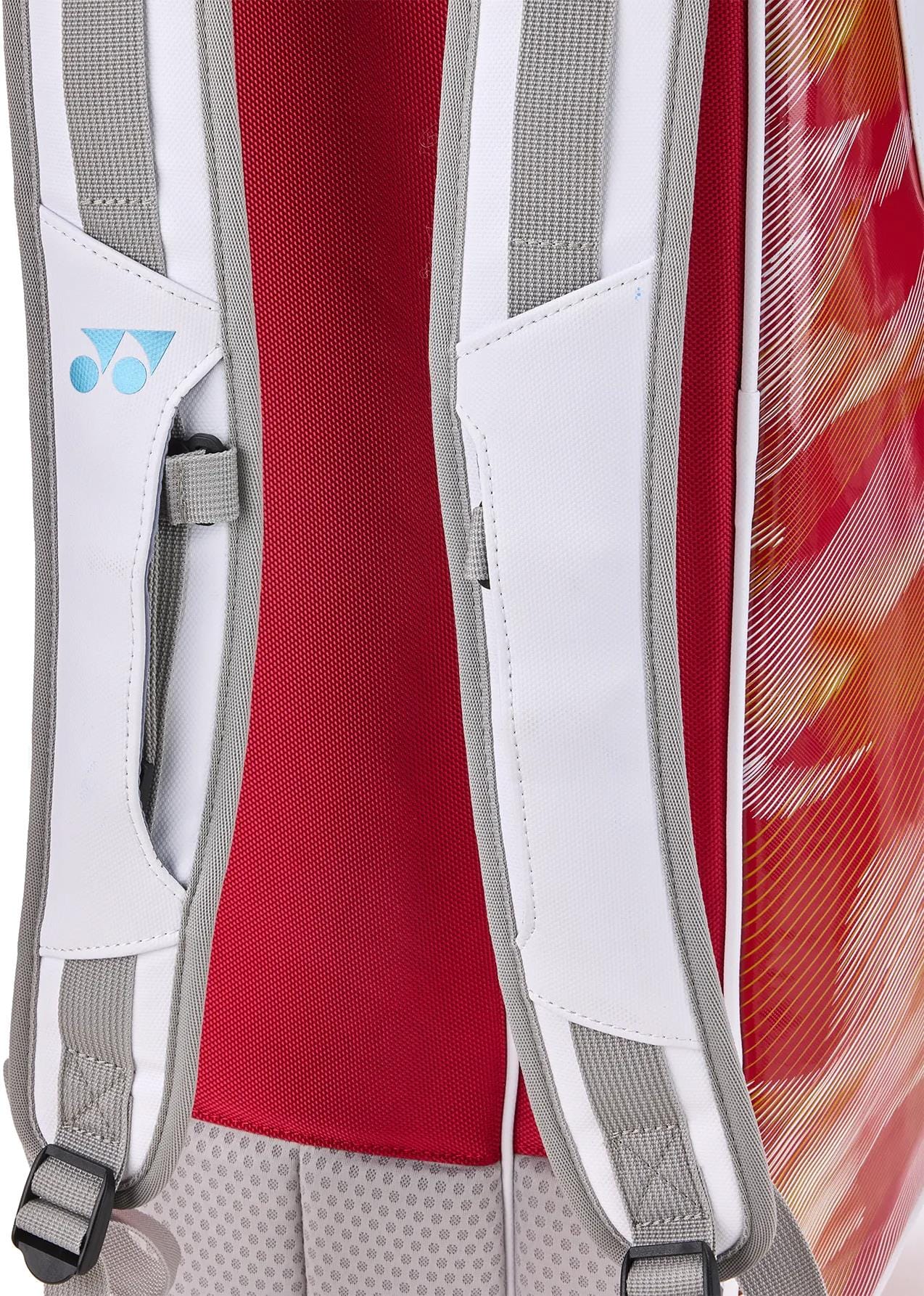 Close-up of the Yonex 02626EX Expert 6 Racket Tennis Bag in white, featuring white and gray shoulder straps, a red mesh back panel, colorful side patterns in red, orange, and yellow, and the Yonex logo on one strap.