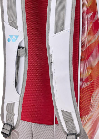 Close-up of the Yonex 02626EX Expert 6 Racket Tennis Bag in white, featuring white and gray shoulder straps, a red mesh back panel, colorful side patterns in red, orange, and yellow, and the Yonex logo on one strap.