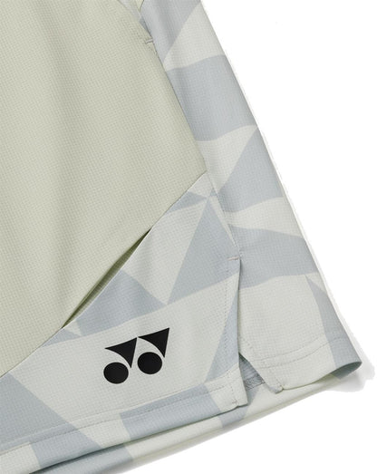 Close-up of breathable knit fabric in light gray and off-white with a geometric pattern, showing the Yonex logo near the hem. The image highlights a seam and part of the angular design on Yonex 15240YX Knit Men's Tennis Shorts - Champagne.