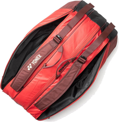 The Yonex 42529EX Team 9 Racket Tennis Bag in Ruby Red features brown straps, a spacious dual-compartment interior when unzipped, and the white Yonex logo printed on one side.