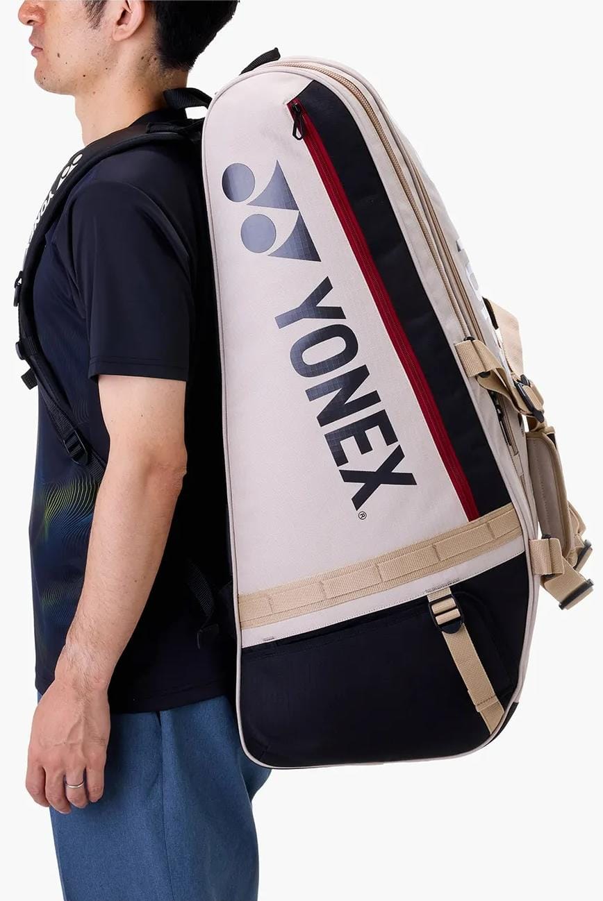 A person with the Yonex BA72629EX Gearlogic 9 Racket Tennis Bag in beige, featuring shoulder straps, is shown in side profile against a white background—ideal for carrying your tennis essentials.