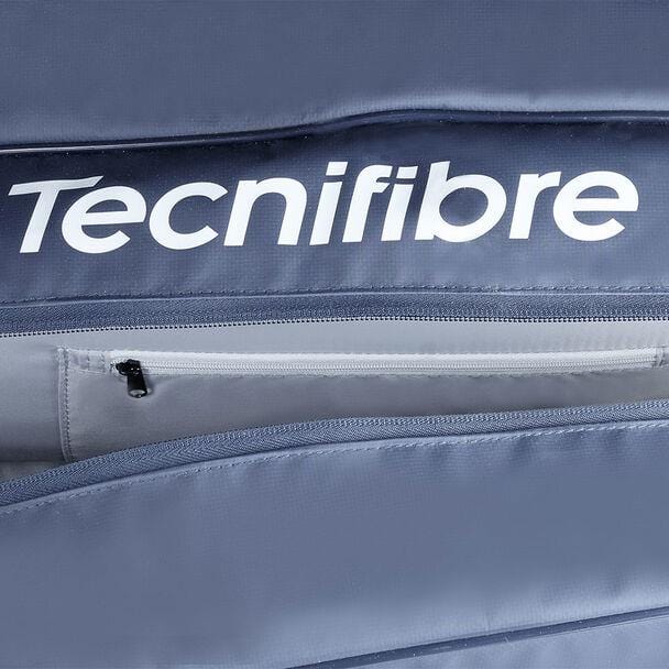 Close-up of a navy blue Tecnifibre Tour Endurance 2023 12 Racket Tennis Bag, showcasing the brand name in white letters. The focus is on a zippered compartment, partially unzipped, revealing a lighter gray interior crafted from durable tarpaulin material.