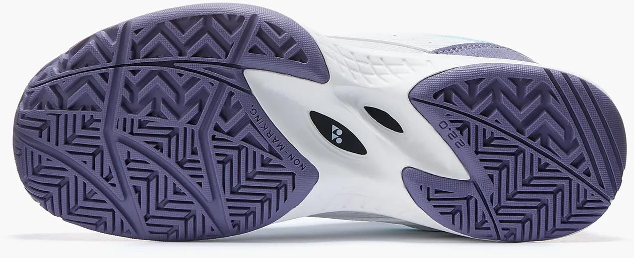 The image displays the sole of Yonex Pro-Move Classic Junior Tennis Shoes - White / Sax, featuring zigzag and herringbone tread patterns for grip and traction, plus Power Cushion Technology for added comfort and shock absorption.