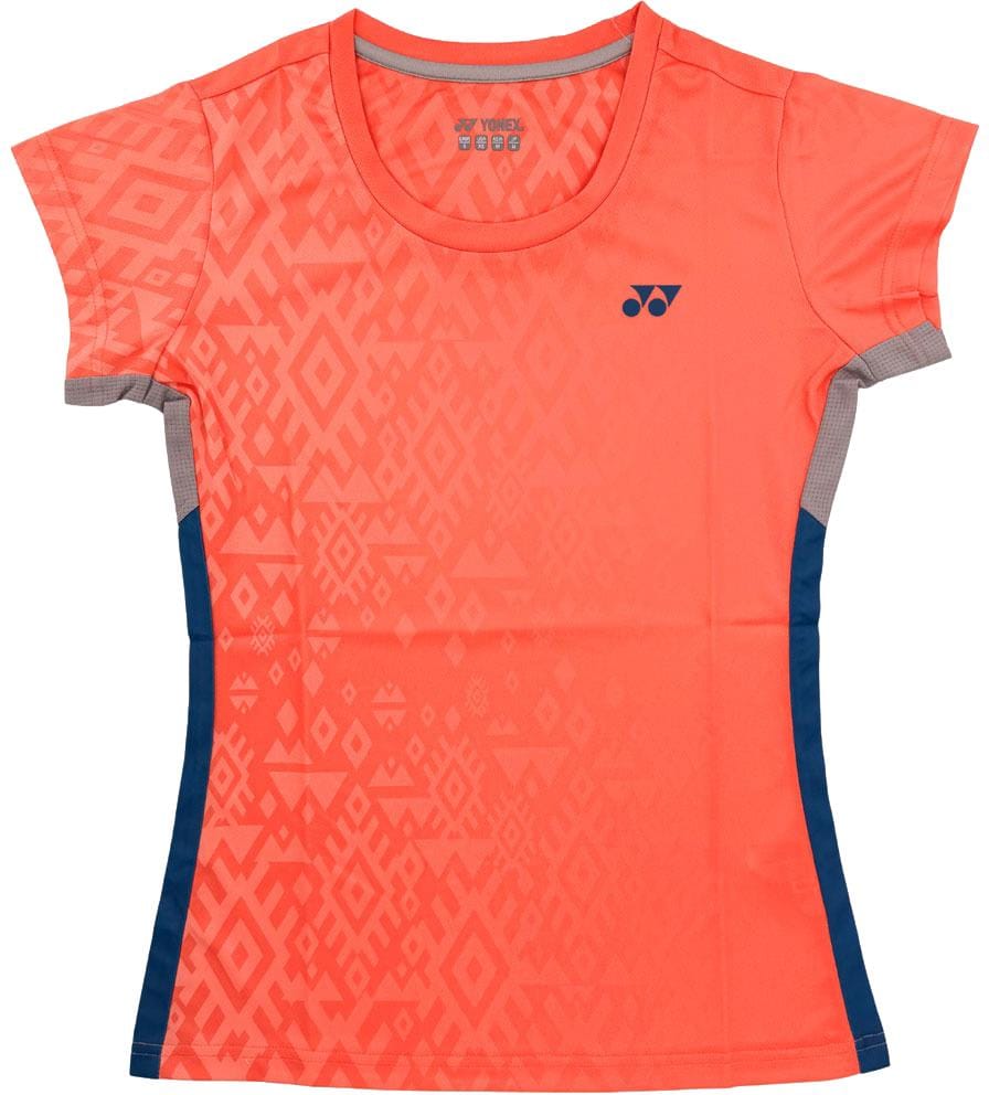 The Yonex YTL11 Womens Tennis T-Shirt - Sunset is a short-sleeved coral tee with geometric patterns, navy blue side panels, and a Yonex logo. Made from breathable, quick-drying fabric for comfort on the court.