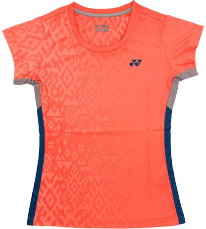 The Yonex YTL11 Womens Tennis T-Shirt - Sunset is a short-sleeved coral tee with geometric patterns, navy blue side panels, and a Yonex logo. Made from breathable, quick-drying fabric for comfort on the court.