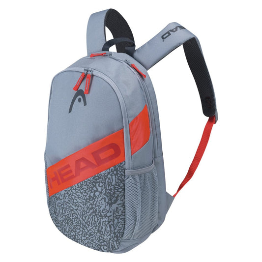 The HEAD Elite Tennis Backpack in Grey Orange highlights black and orange accents with the brand name prominently displayed in bold orange letters. It includes an integrated racquet compartment, dual shoulder straps, a side mesh pocket, and a textured pattern on the lower front.