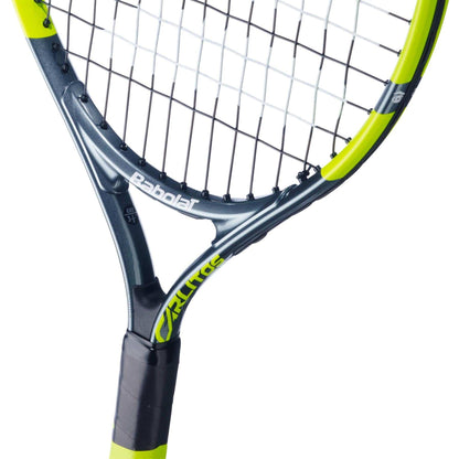 Close-up of the Babolat Carlitos Junior 21 Tennis Racket by Babolat, highlighting its lightweight design, black grip, grey frame with neon yellow accents, visible strings, and branding on the throat and frame.