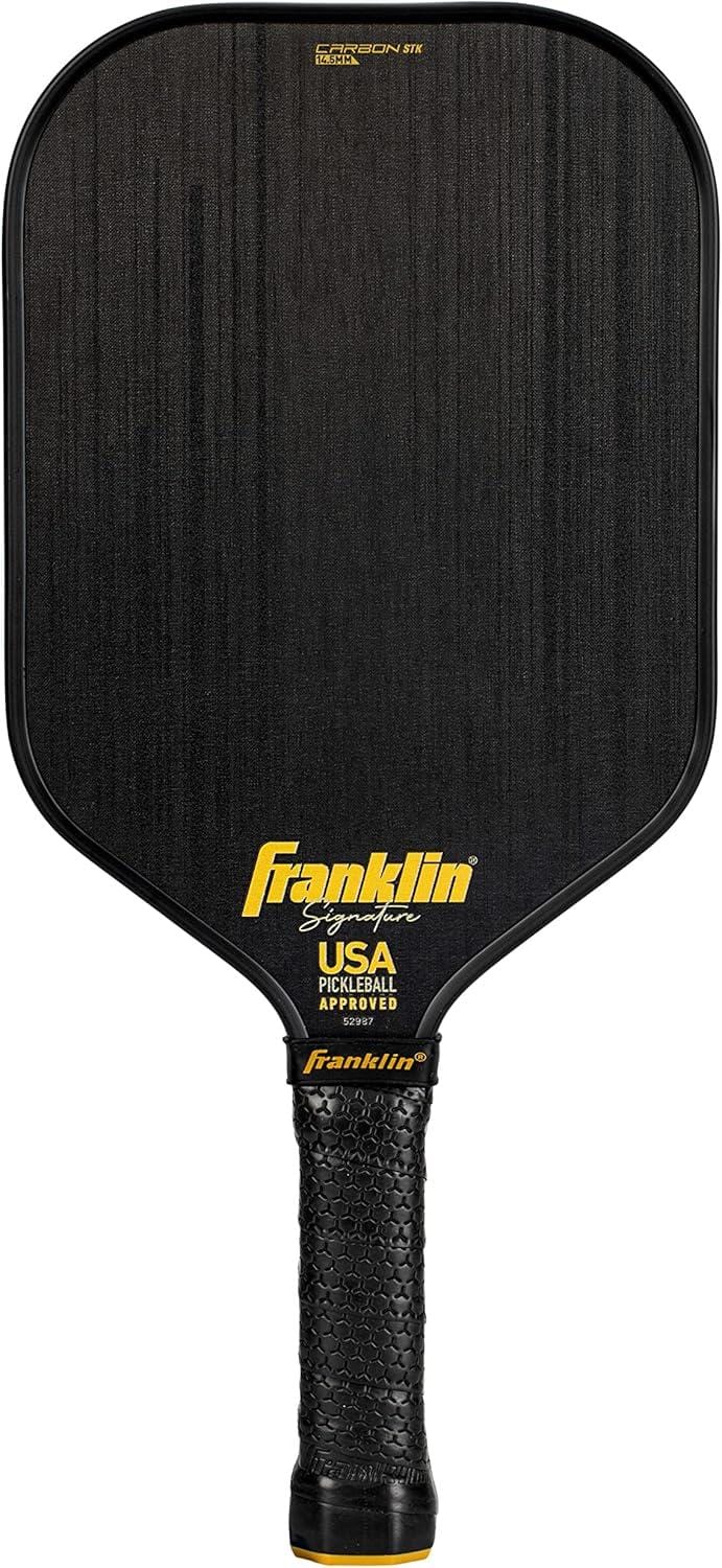 The Franklin Carbon STK 14.5mm Pickleball Paddle in black features a carbon fiber surface, black handle, yellow Franklin branding, and "USA Pickleball Approved" printed near the neck.