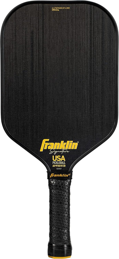 The Franklin Carbon STK 14.5mm Pickleball Paddle in black features a carbon fiber surface, black handle, yellow Franklin branding, and "USA Pickleball Approved" printed near the neck.