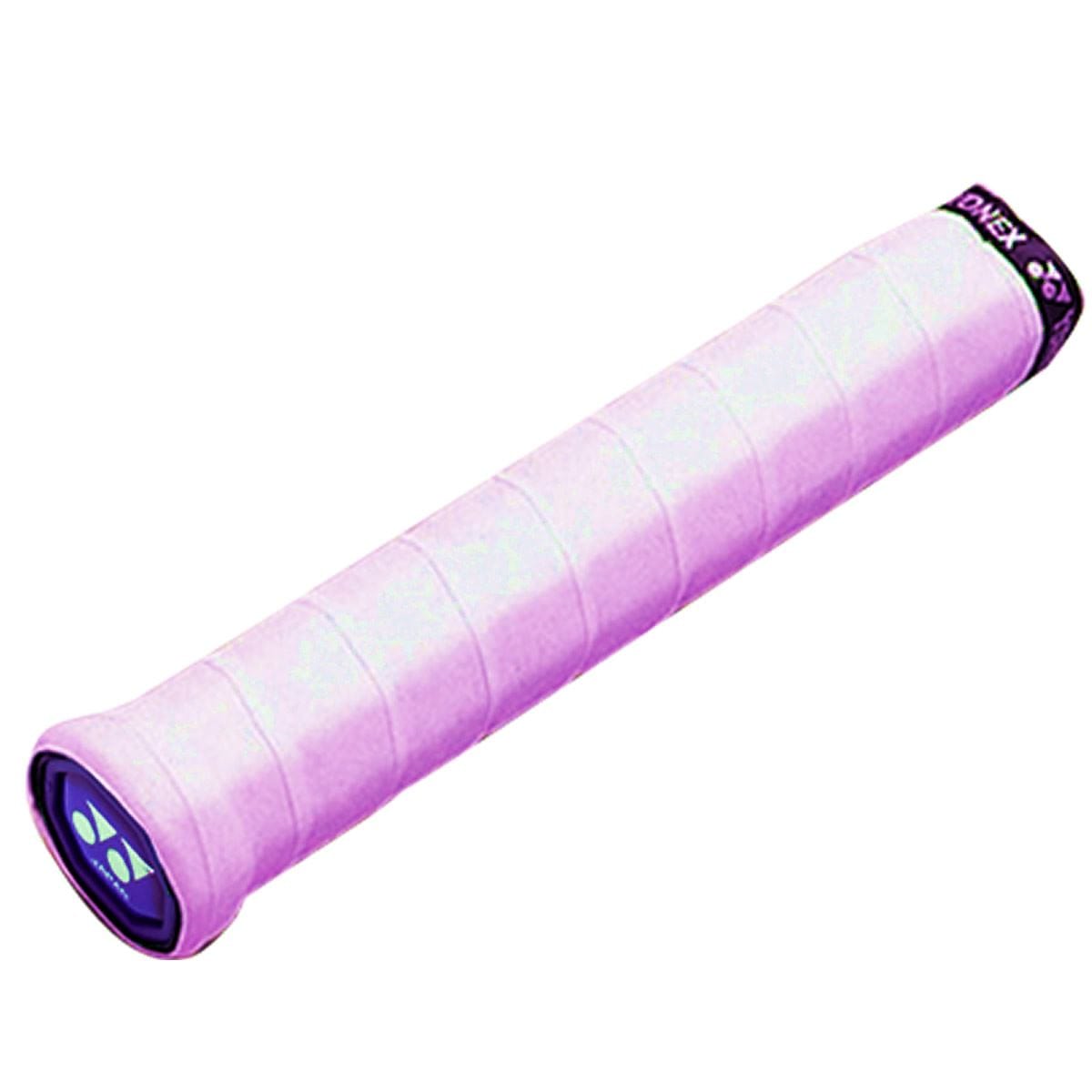 A close-up of a pink Yonex AC102EX Super Grap Tennis Overgrip, showcasing its textured surface and superior sweat absorption, complete with the Yonex logo at one end. The overgrip is cylindrical and wrapped in a spiral pattern.