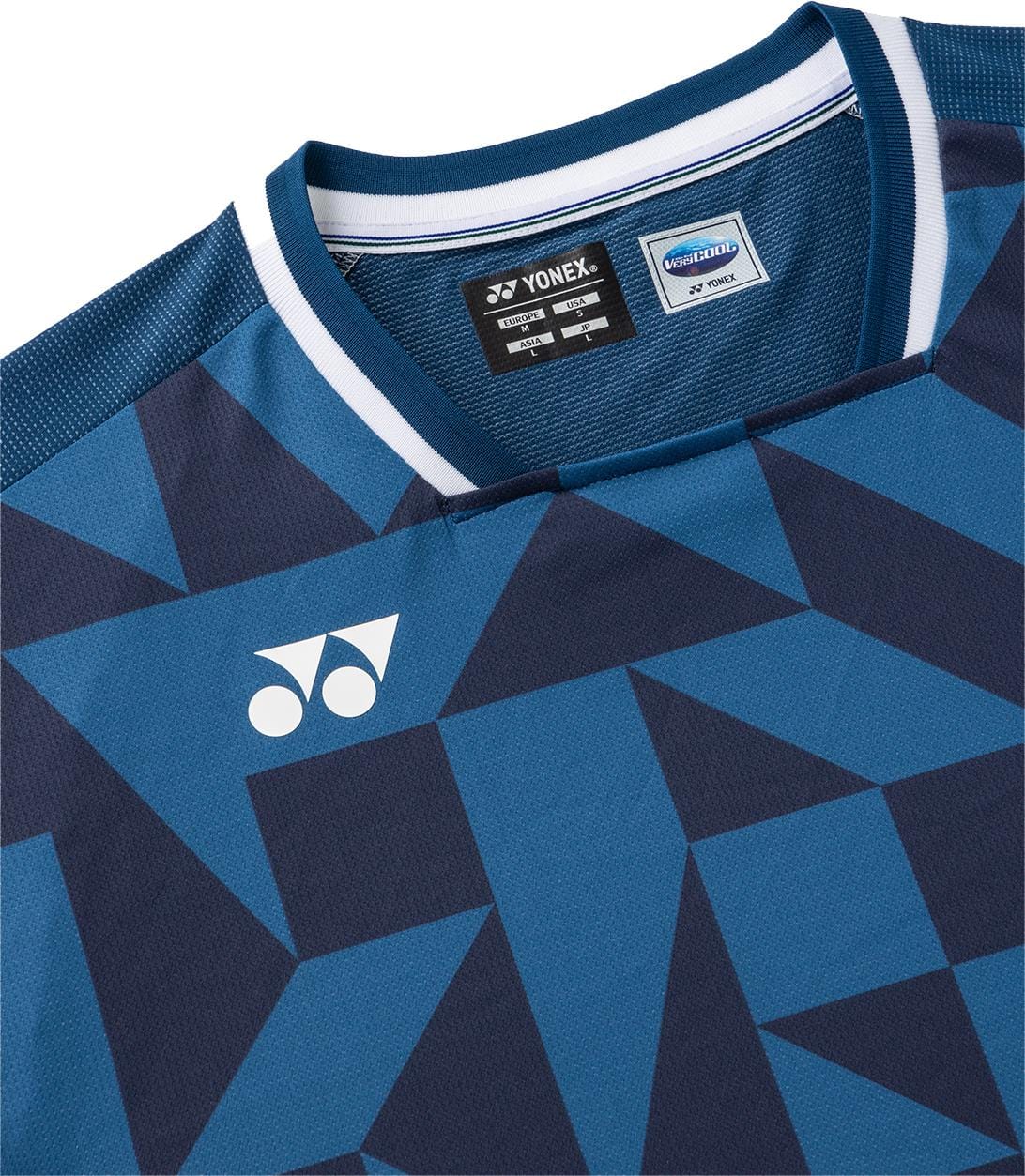 A close-up of the Yonex 10712YX Crew Neck Men's Tennis T-Shirt in indigo blue, featuring geometric dark blue patterns, a white Yonex logo on the chest, and sports performance Verycool tags visible inside the collar.
