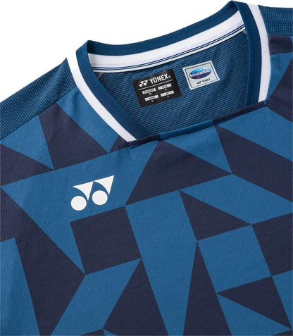 A close-up of the Yonex 10712YX Crew Neck Men's Tennis T-Shirt in indigo blue, featuring geometric dark blue patterns, a white Yonex logo on the chest, and sports performance Verycool tags visible inside the collar.
