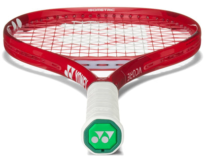 A close-up of the Yonex VCORE 26 Junior Ruby Red 2026 Tennis Racket showcases its white grip, green Yonex logo on the butt cap, red frame, white and red strings, and advanced isometric technology for enhanced play.