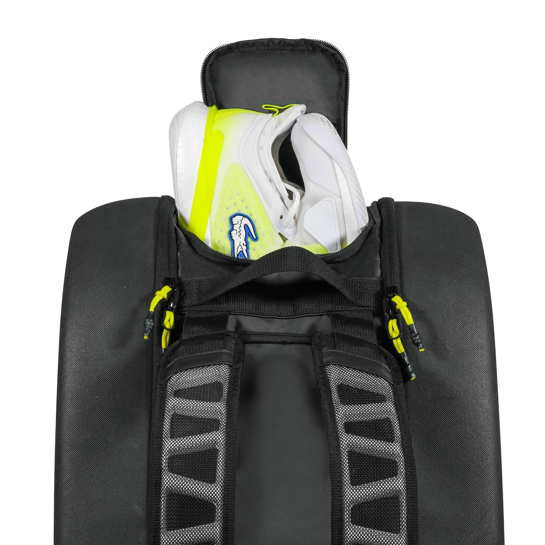 A pair of white athletic shoes with yellow accents are stored in the open top compartment of the spacious Tecnifibre Reform L Tennis Racket Bag - Black, featuring black, gray, and yellow zipper details.