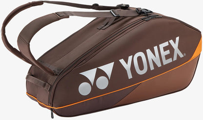 The Yonex 92426EX 6 Racket Pro Tennis Bag in Espresso Brown features two carrying straps, prominent Yonex branding in large white letters on the side, and orange accents, making it the ideal choice for organizing and transporting all your tennis gear to the court.