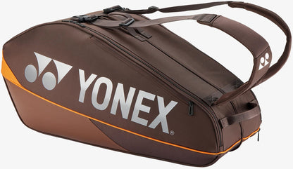 The Yonex 92426EX 6 Racket Pro Tennis Bag in Espresso Brown features striking orange accents and a bold white Yonex logo, along with convenient shoulder straps and multiple zippered compartments. Designed for both style and functionality, this bag provides ample space for up to six rackets and all your court essentials.
